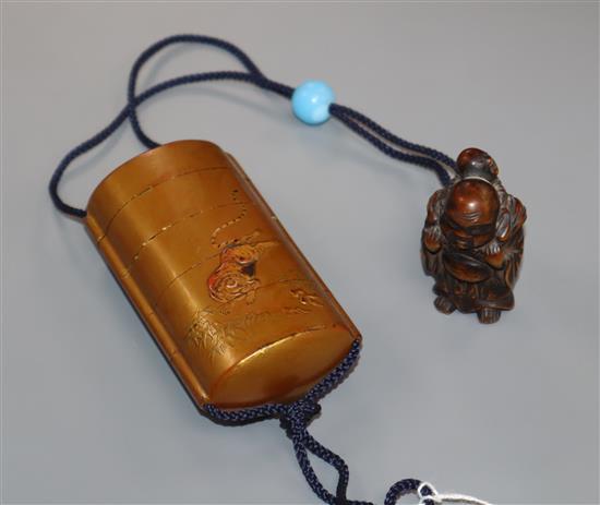 A Japanese gold lacquer four case inro with relief tiger and a hotei carved wood netsuke and blue glass ojime